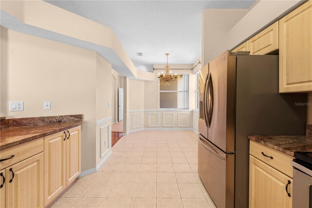 4201 Silver Berry Ct, Spring Hill, FL 34609 - kitchen with light brown cabinetry, a chandelier, light tile patterned floors, a decorative wall, and a wainscoted wall