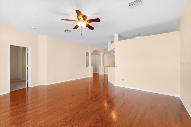 4201 Silver Berry Ct, Spring Hill, FL 34609 - unfurnished living room featuring ceiling fan, decorative columns, baseboards, wood finished floors, and arched walkways