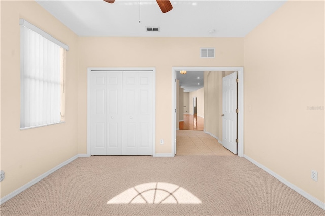 unfurnished bedroom with ceiling fan, a closet, and light colored carpet