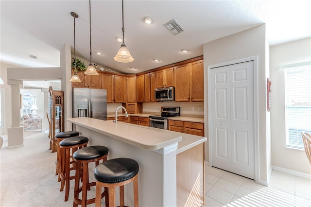 kitchen with plenty of natural light, decorative light fixtures, a center island with sink, and appliances with stainless steel finishes