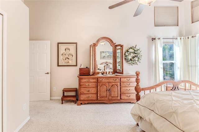 carpeted bedroom with ceiling fan and a high ceiling