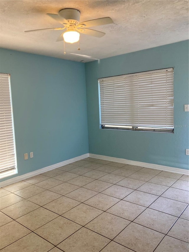 spare room featuring ceiling fan, light tile patterned flooring, and a textured ceiling