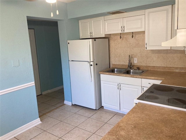 kitchen with sink, light tile patterned floors, tasteful backsplash, white fridge, and white cabinets