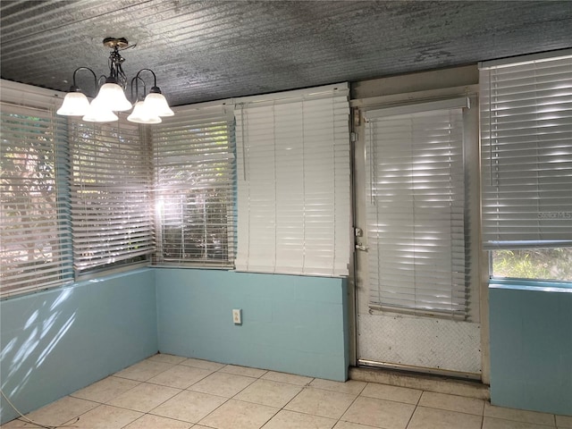 tiled spare room with an inviting chandelier