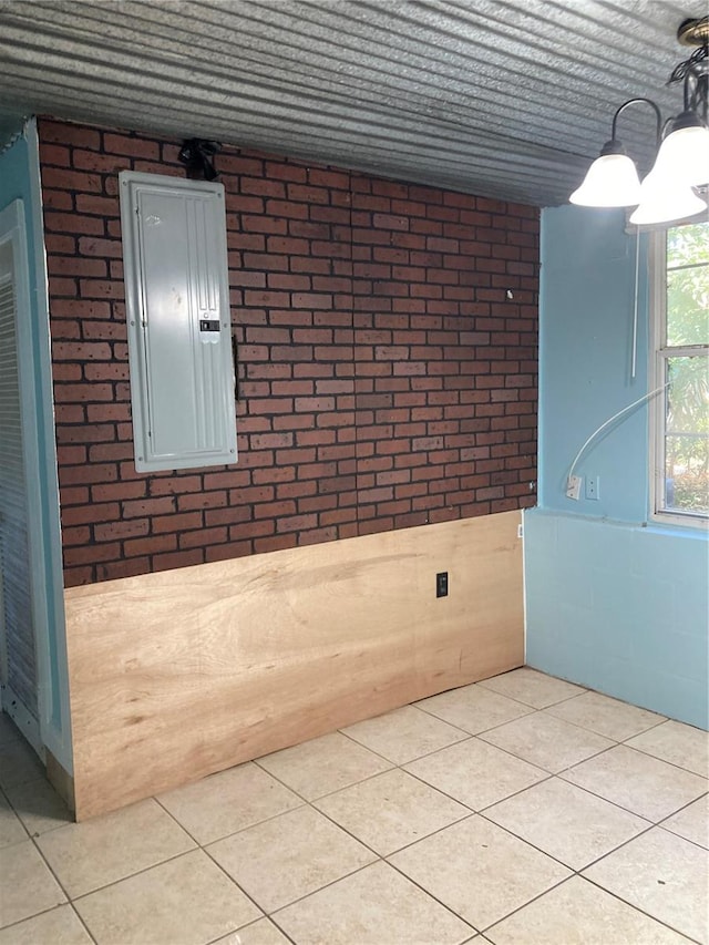 interior space featuring a notable chandelier, brick wall, and electric panel