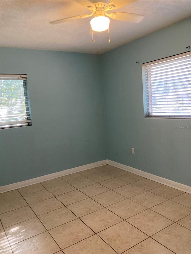 tiled empty room featuring ceiling fan