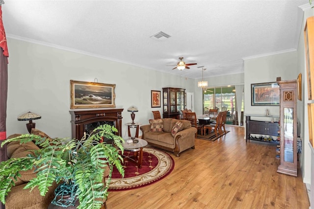 living room featuring crown molding, ceiling fan, light hardwood / wood-style floors, and a textured ceiling