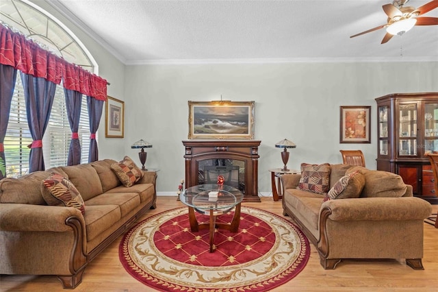 living room featuring ceiling fan, a high end fireplace, a textured ceiling, hardwood / wood-style flooring, and ornamental molding