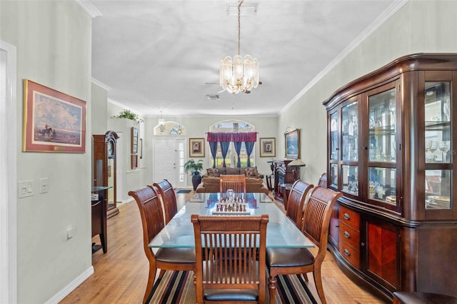 dining room featuring an inviting chandelier, a healthy amount of sunlight, crown molding, and light hardwood / wood-style flooring