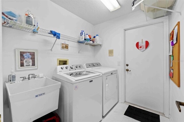 laundry area featuring a textured ceiling, washer and dryer, and sink