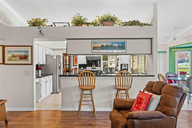 kitchen with white cabinets, light hardwood / wood-style floors, kitchen peninsula, and ornamental molding