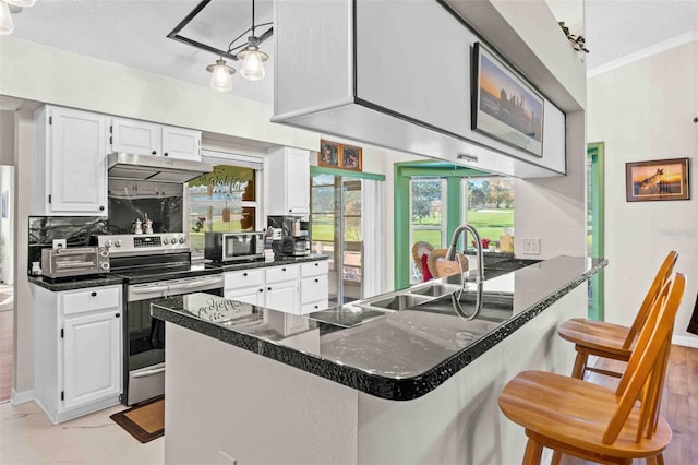 kitchen with white cabinets, a kitchen breakfast bar, sink, electric range, and kitchen peninsula