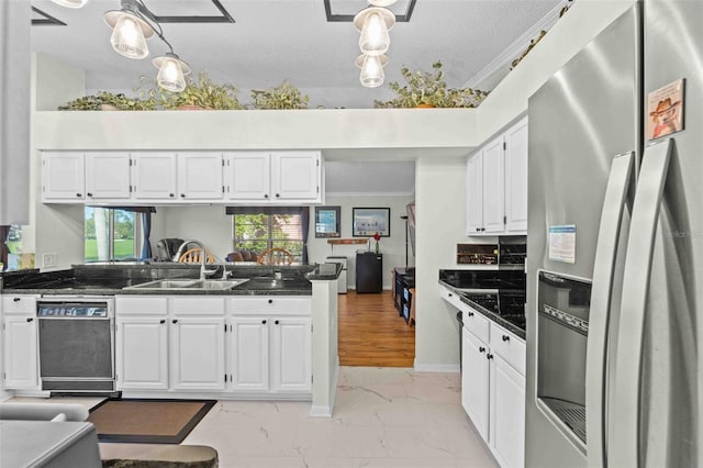 kitchen featuring white cabinetry, stainless steel fridge, decorative light fixtures, and ornamental molding