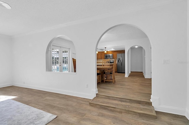 spare room featuring a textured ceiling, light wood-type flooring, french doors, and ceiling fan