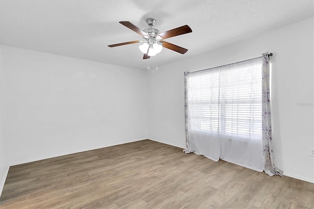 empty room featuring ceiling fan, a textured ceiling, and light hardwood / wood-style flooring