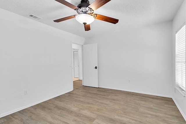 empty room featuring a textured ceiling, light hardwood / wood-style flooring, and a healthy amount of sunlight