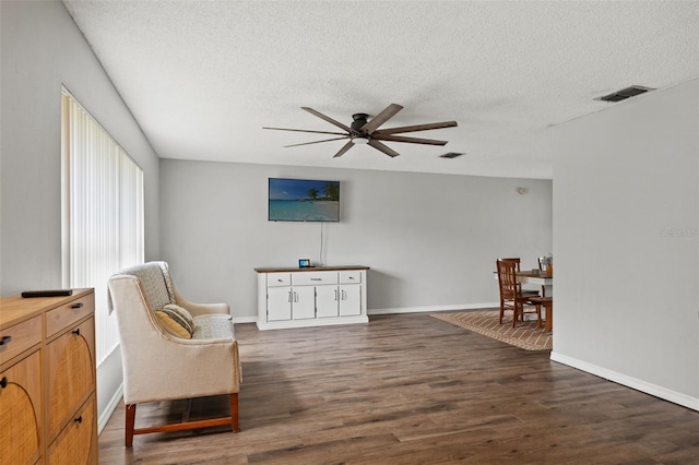 sitting room with ceiling fan, dark hardwood / wood-style flooring, and a textured ceiling