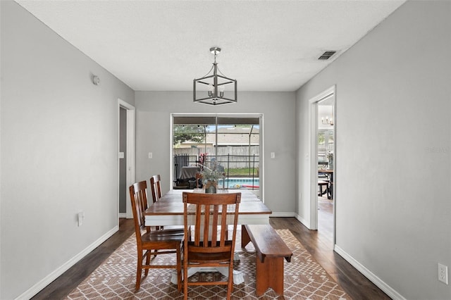 dining space featuring a textured ceiling, dark hardwood / wood-style floors, and a notable chandelier