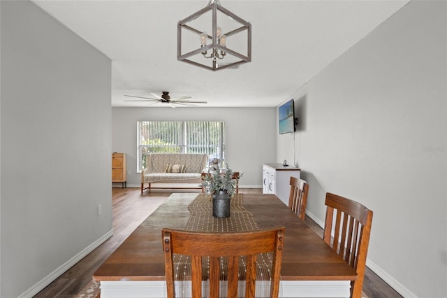 dining room with ceiling fan with notable chandelier and dark wood-type flooring