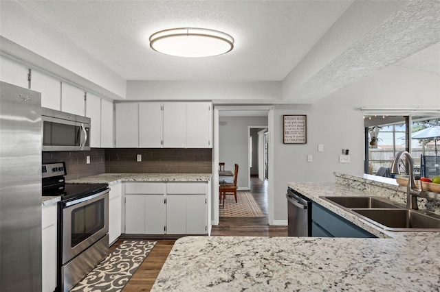 kitchen with appliances with stainless steel finishes, a textured ceiling, white cabinetry, and sink