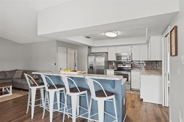 kitchen with white cabinets, decorative backsplash, stainless steel appliances, and dark wood-type flooring