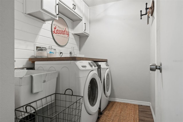 laundry room featuring cabinets, wood-type flooring, a textured ceiling, and washer and clothes dryer