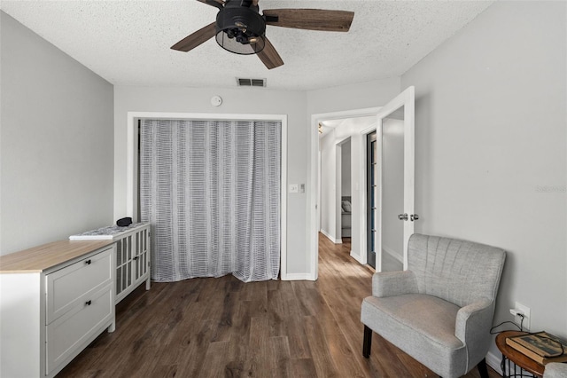 sitting room featuring ceiling fan, dark hardwood / wood-style flooring, and a textured ceiling