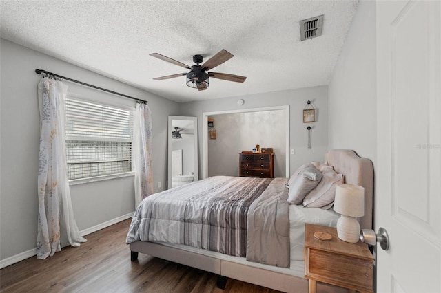 bedroom with a textured ceiling, dark hardwood / wood-style flooring, and ceiling fan