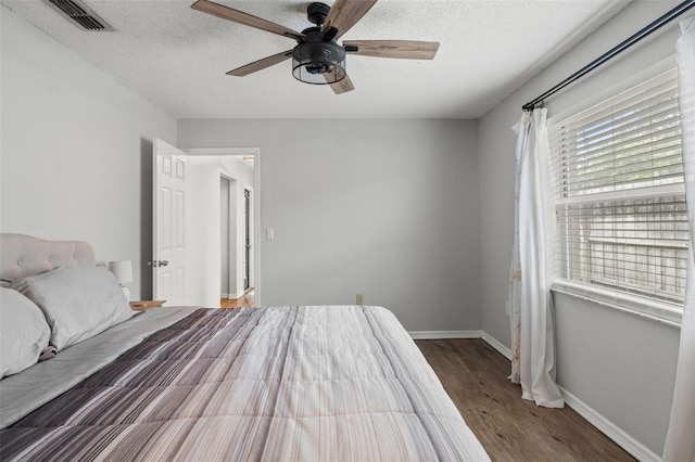 bedroom with a textured ceiling, hardwood / wood-style flooring, and ceiling fan