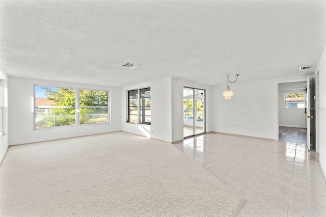 tiled spare room with a textured ceiling, an inviting chandelier, and plenty of natural light