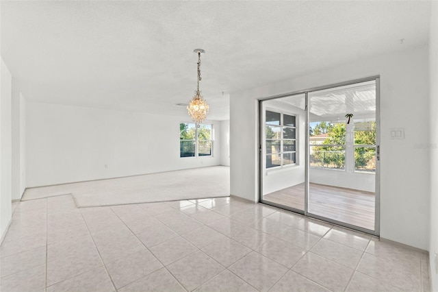 spare room featuring light tile patterned floors, a textured ceiling, and an inviting chandelier