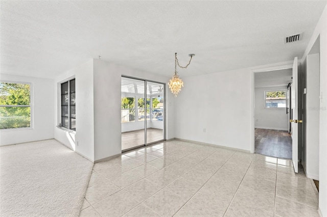 unfurnished room featuring light tile patterned floors, a textured ceiling, and an inviting chandelier