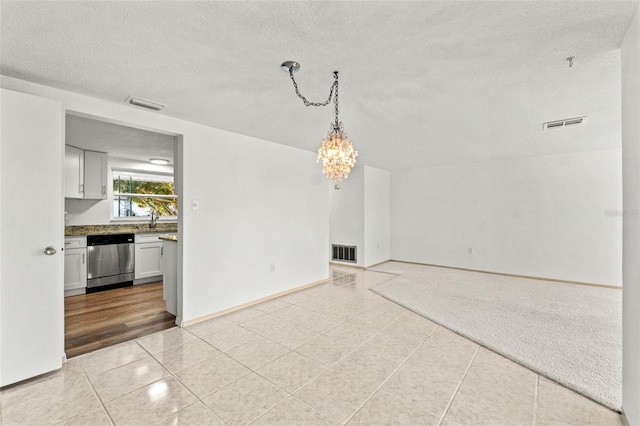 empty room featuring light tile patterned floors, a chandelier, and a textured ceiling