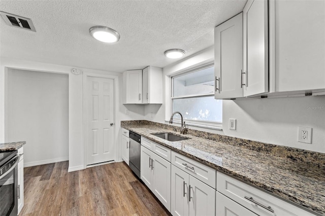 kitchen with dark hardwood / wood-style flooring, stainless steel appliances, sink, stone counters, and white cabinetry