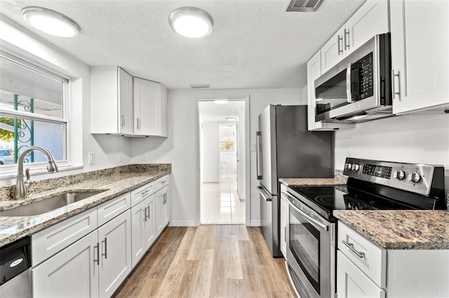 kitchen featuring light hardwood / wood-style floors, white cabinetry, sink, and appliances with stainless steel finishes