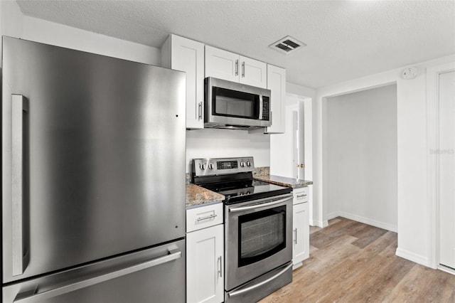 kitchen featuring light stone counters, appliances with stainless steel finishes, a textured ceiling, white cabinets, and light wood-type flooring