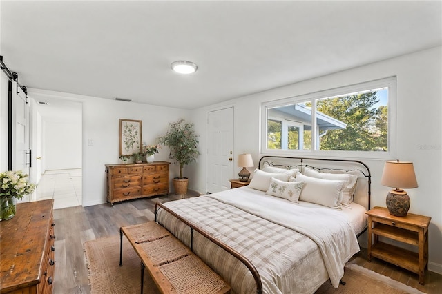 bedroom with light wood-type flooring and a barn door