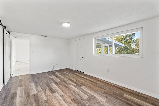 empty room featuring hardwood / wood-style floors, a barn door, and a textured ceiling