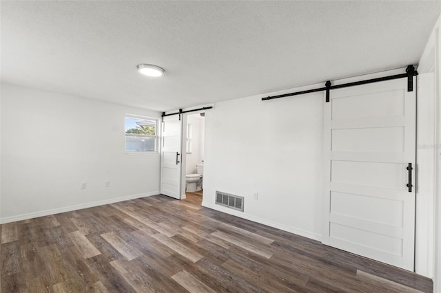 interior space featuring hardwood / wood-style flooring, a barn door, and a textured ceiling