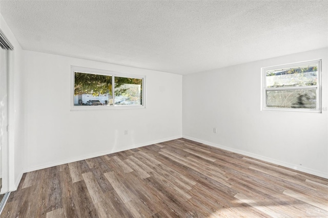 unfurnished room with a healthy amount of sunlight, light wood-type flooring, and a textured ceiling