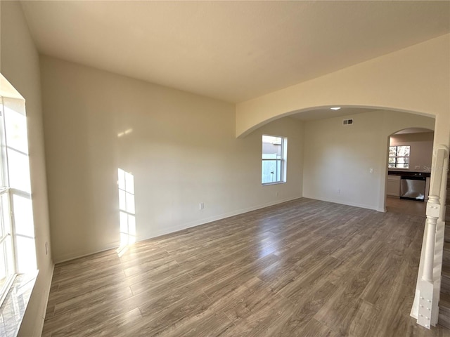 spare room with visible vents, plenty of natural light, and wood finished floors