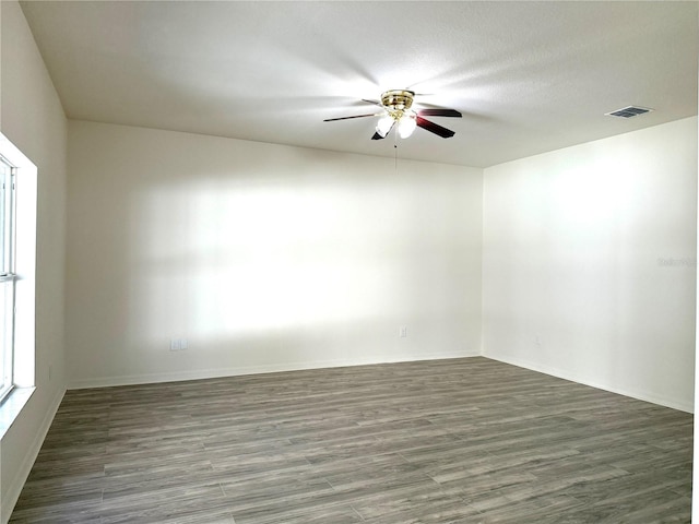 empty room with a textured ceiling, wood finished floors, visible vents, and a ceiling fan