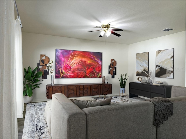 living area with visible vents, a ceiling fan, and wood finished floors