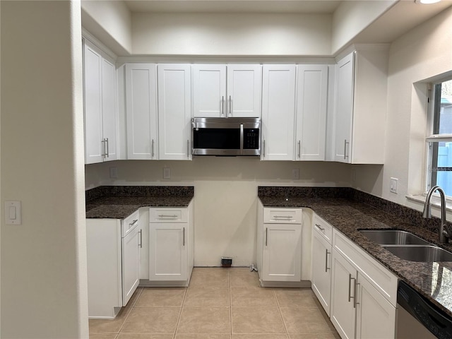 kitchen featuring dark stone countertops, white cabinetry, stainless steel appliances, and a sink