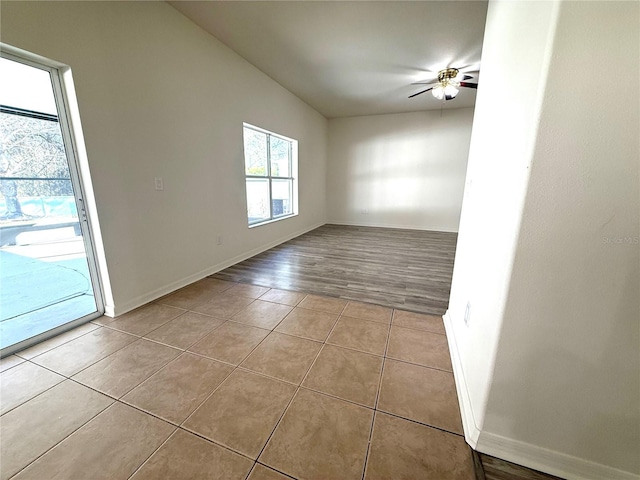 tiled empty room with ceiling fan and baseboards