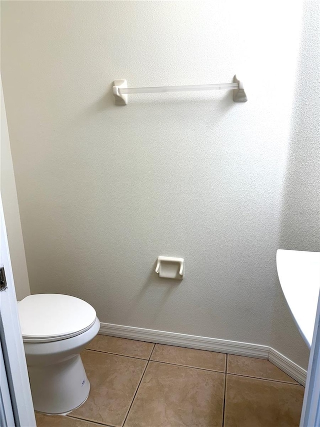 bathroom featuring toilet, baseboards, and tile patterned floors