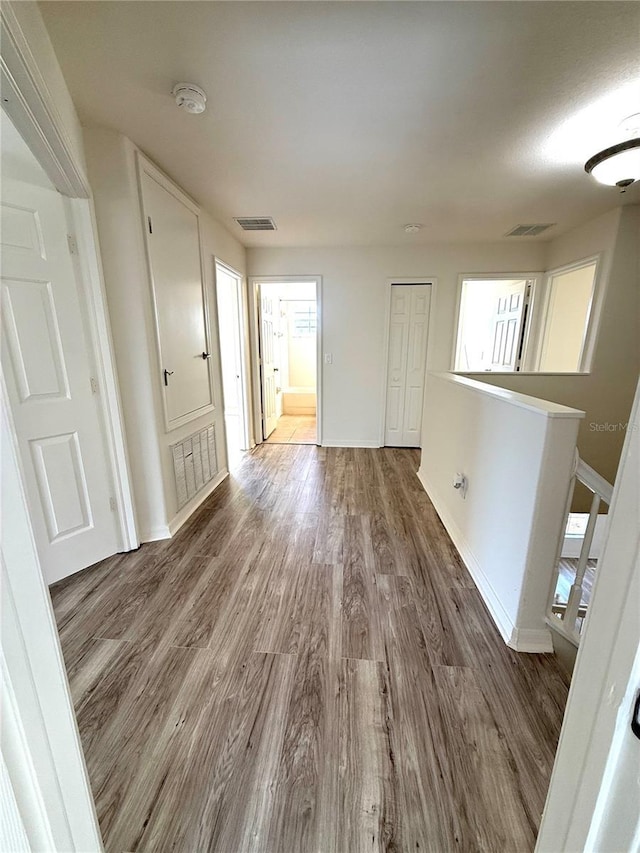 spare room featuring wood finished floors, visible vents, and baseboards