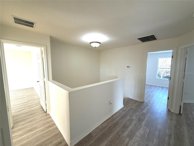 corridor featuring wood finished floors, an upstairs landing, and visible vents