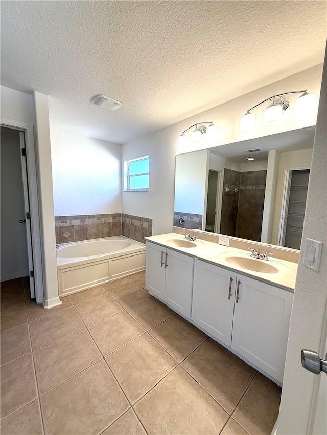 bathroom with a sink, a bath, tile patterned floors, double vanity, and a stall shower