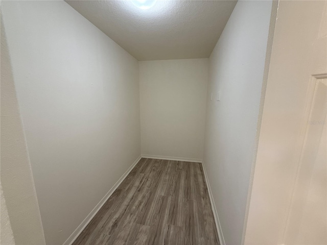 hall featuring dark wood-style floors, baseboards, and a textured ceiling